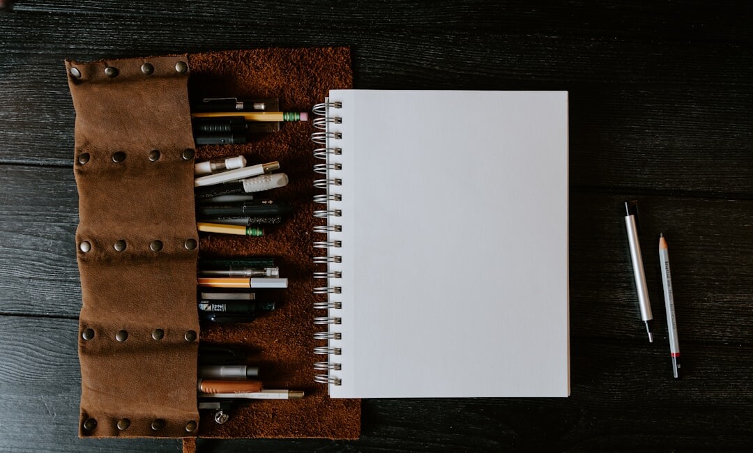 Close-up of an open leather notebook with handwritten notes and a fountain pen on a wooden table
